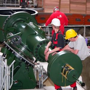 Bauarbeiter mit Helm an der Montierung eines Teleskops